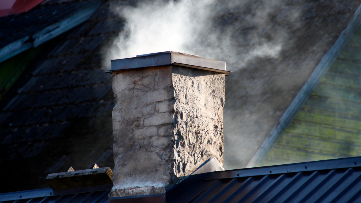 smoking old brick chimney on the roof of a village house