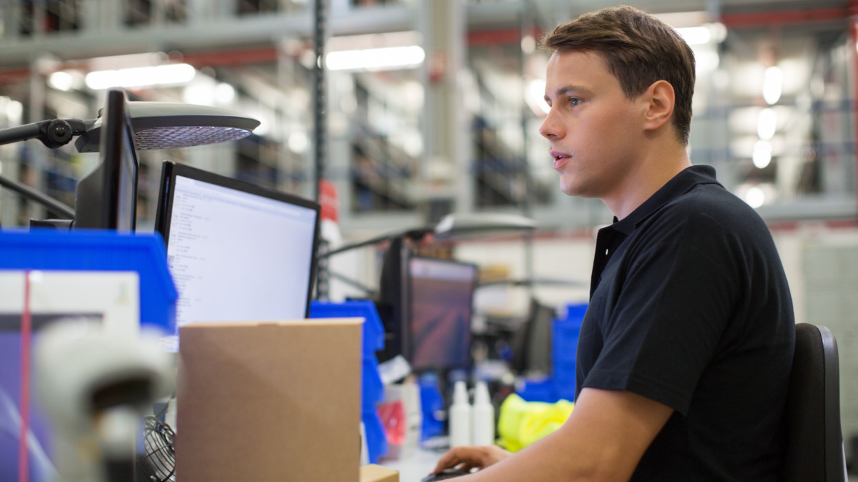 Side view of male employee using computer in logistics center