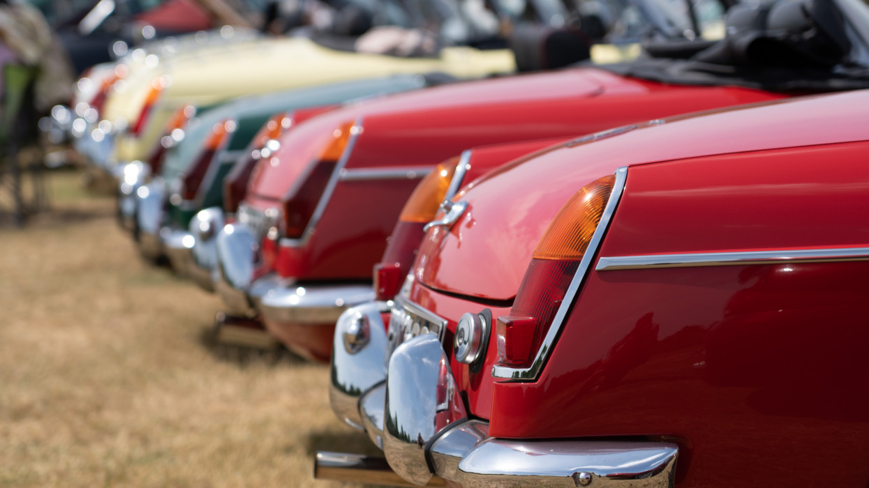 A group of British Classic sports cars are parked up in a classic car meeting. The rear end, lights and rear bumpers are on show. Image taken in July 2022 in Hampshire England