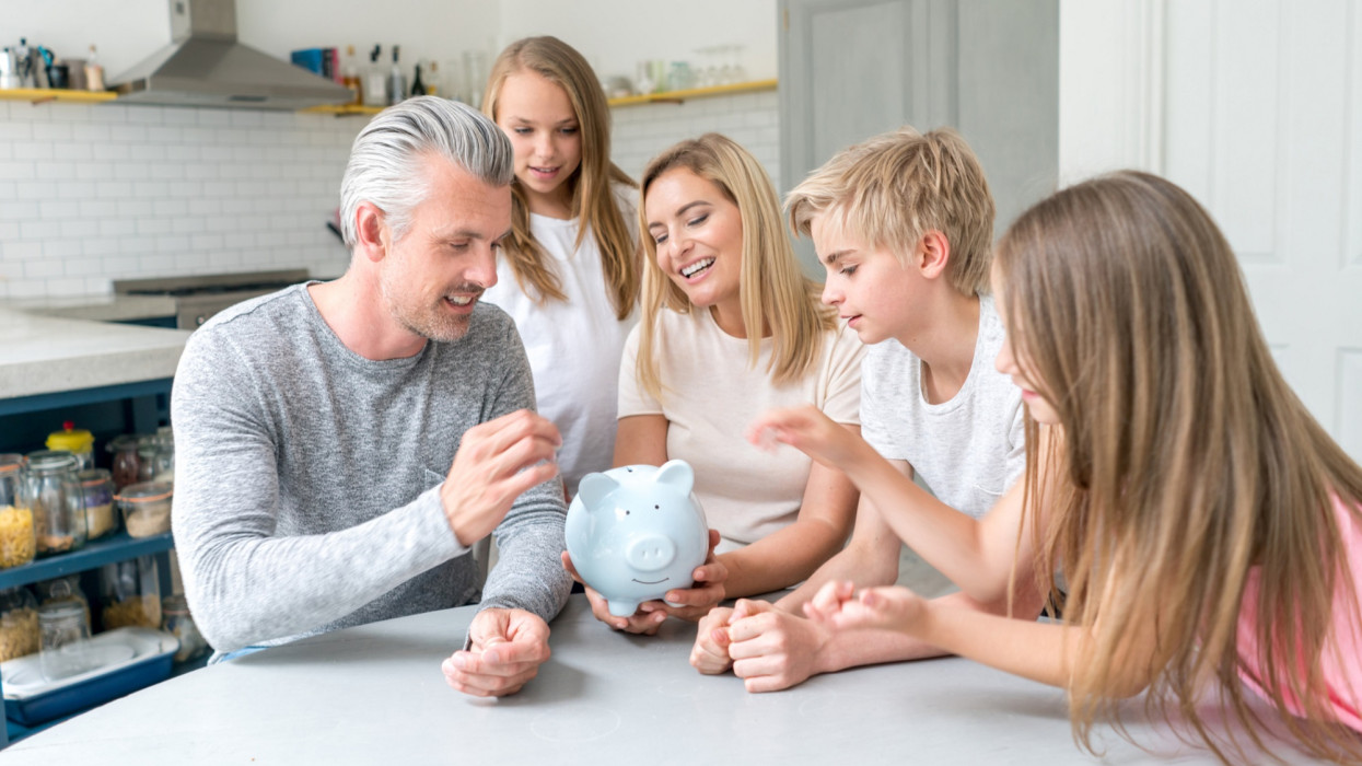 Portrait of a happy Caucasian family saving money in a piggybank - home finances concepts