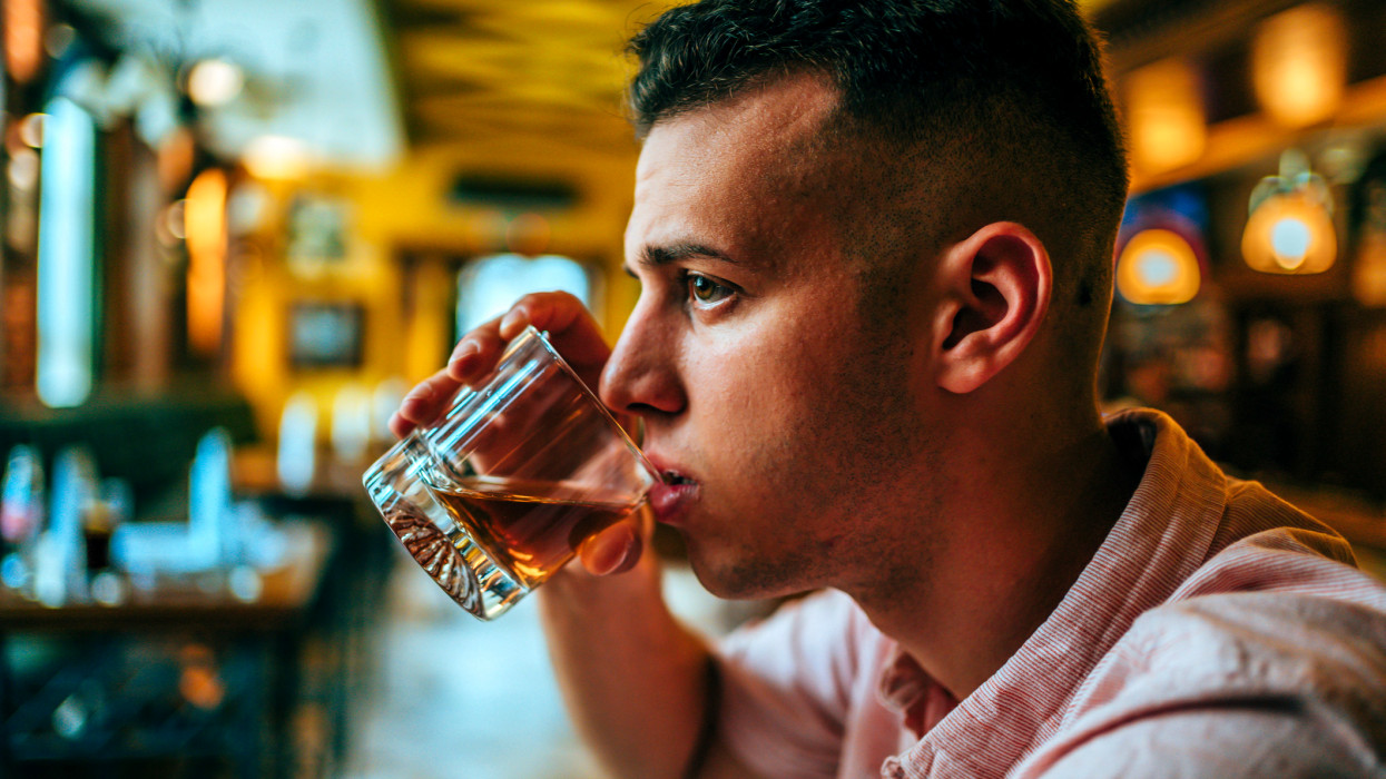 Portrait of young man sitting at the bar and drinking by himself
