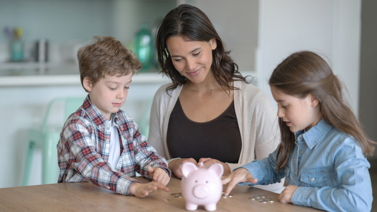 Cute kids counting money after opening their piggybank with their mom at home - Lifestyles