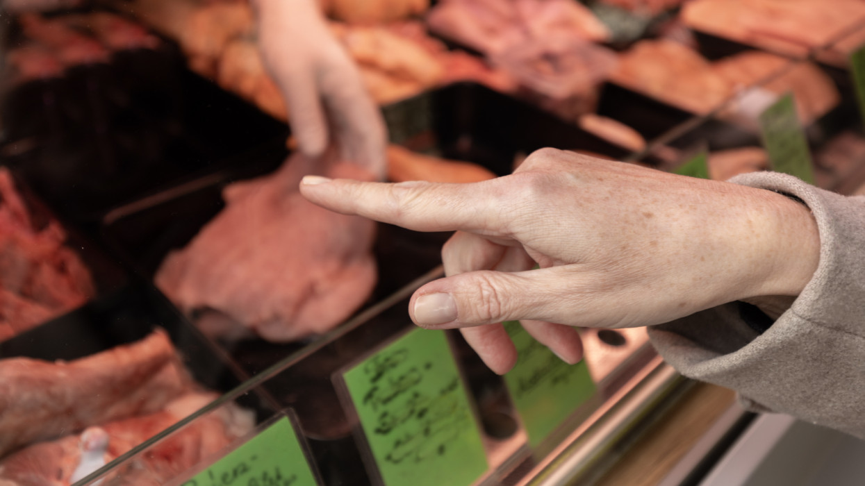 A woman points to an item in a butchers shop that she wants to buy. Shopping market, Austria, Salzburg. High quality photo
