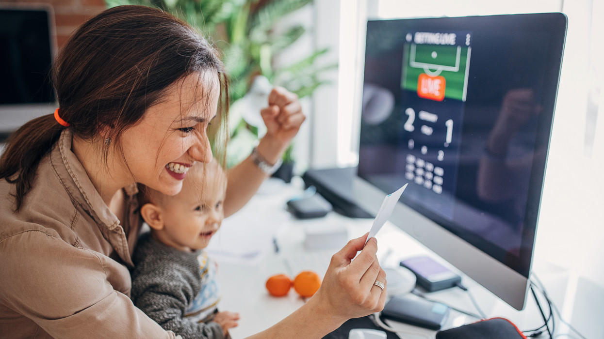 Two people, mother businesswoman and her baby boy son together in modern office at home. They are sports betting online together.