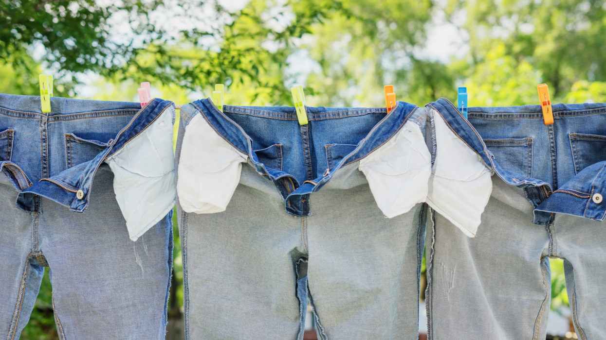 The washed jeans hang on a clothesline. Pockets turned inside out. Drying clothes on the street. Life style.