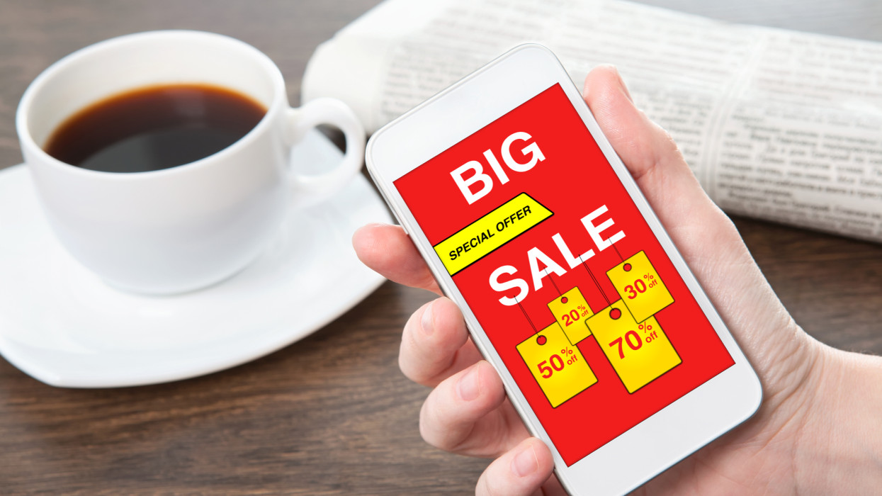 woman hand holding phone with big sale on screen