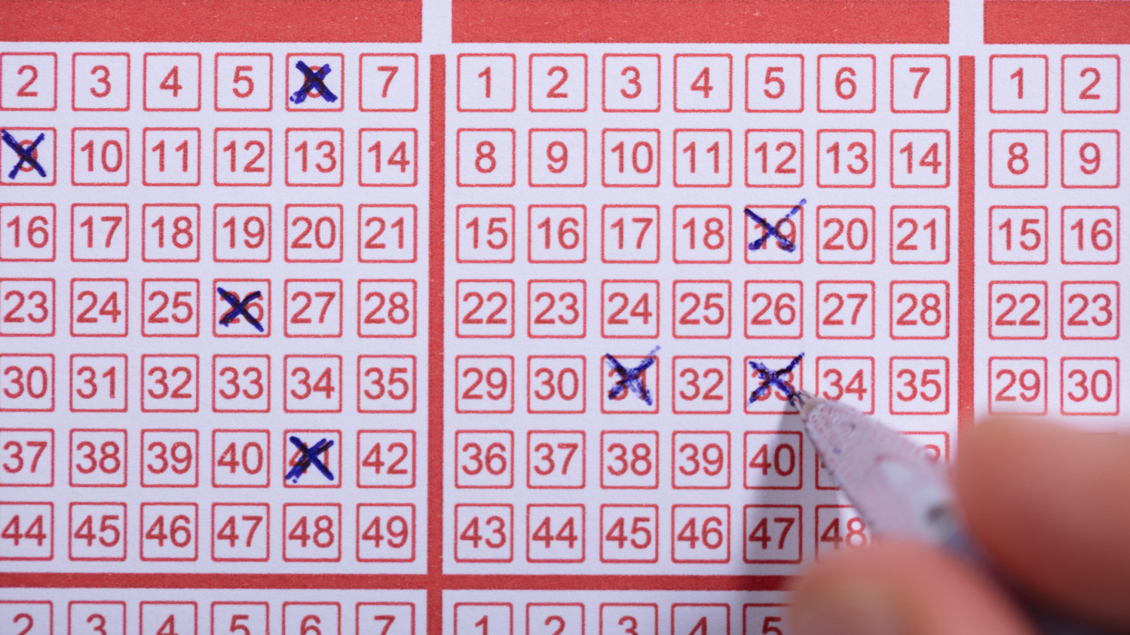Close-up Of A Person Marking Number On Lottery Ticket With Pen