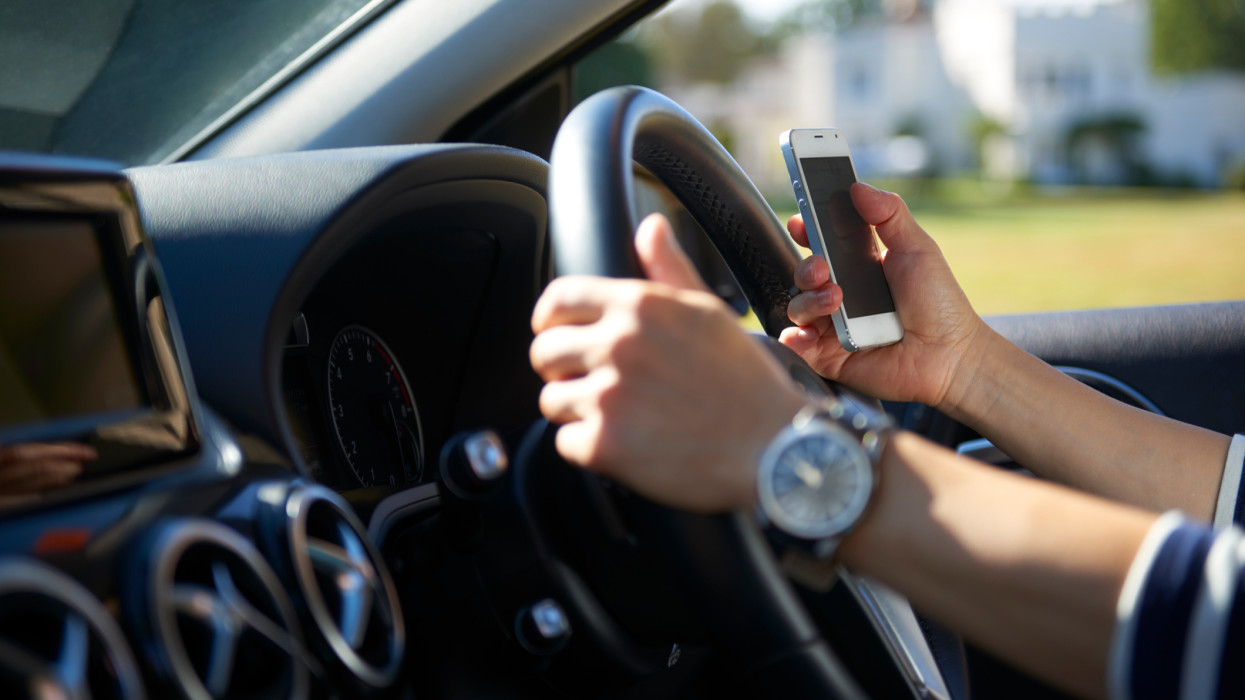 Young woman texting while driving