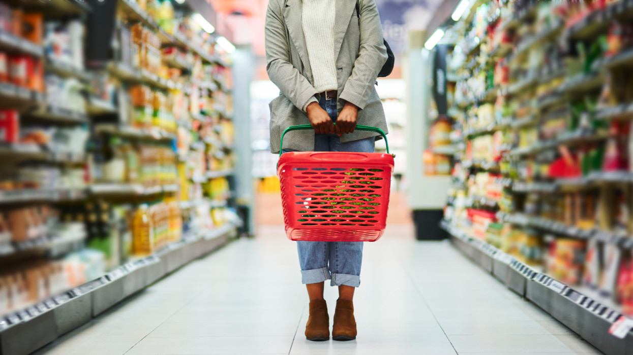 Supermarket aisle, woman legs and basket for shopping in grocery store. Customer, organic grocery shopping and healthy food on groceries sale shelf or eco friendly retail purchase in health shop