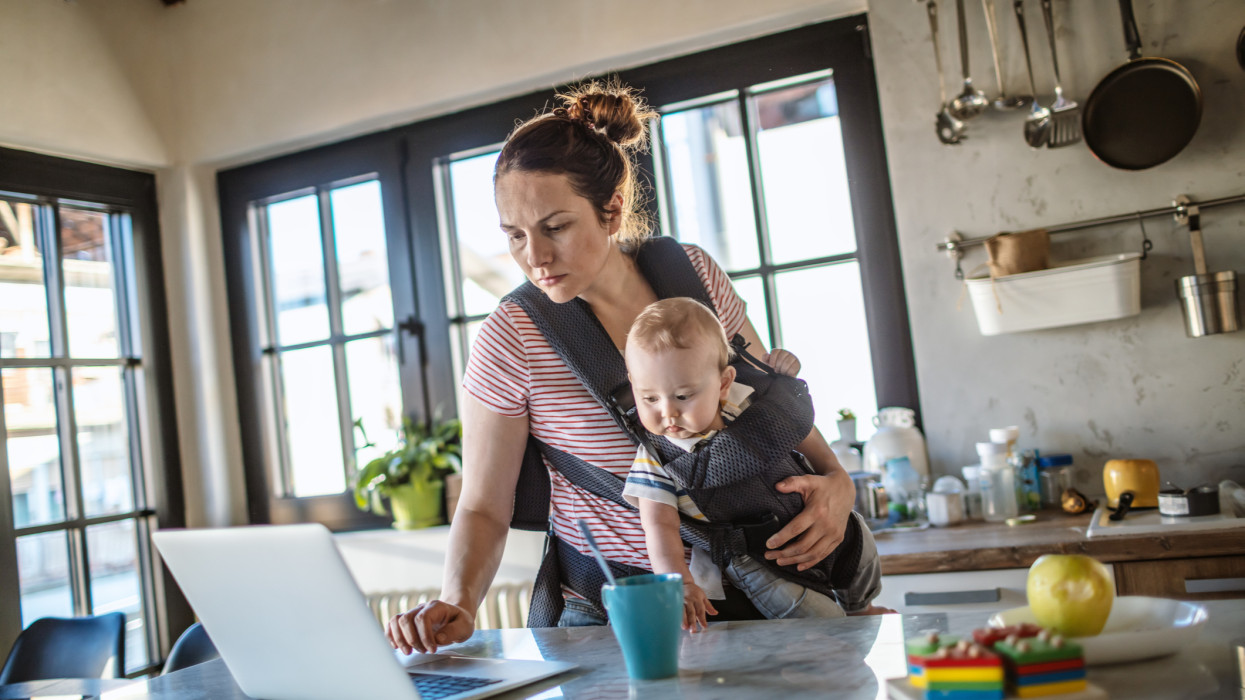 Photo of young mum who is working from home with baby boy