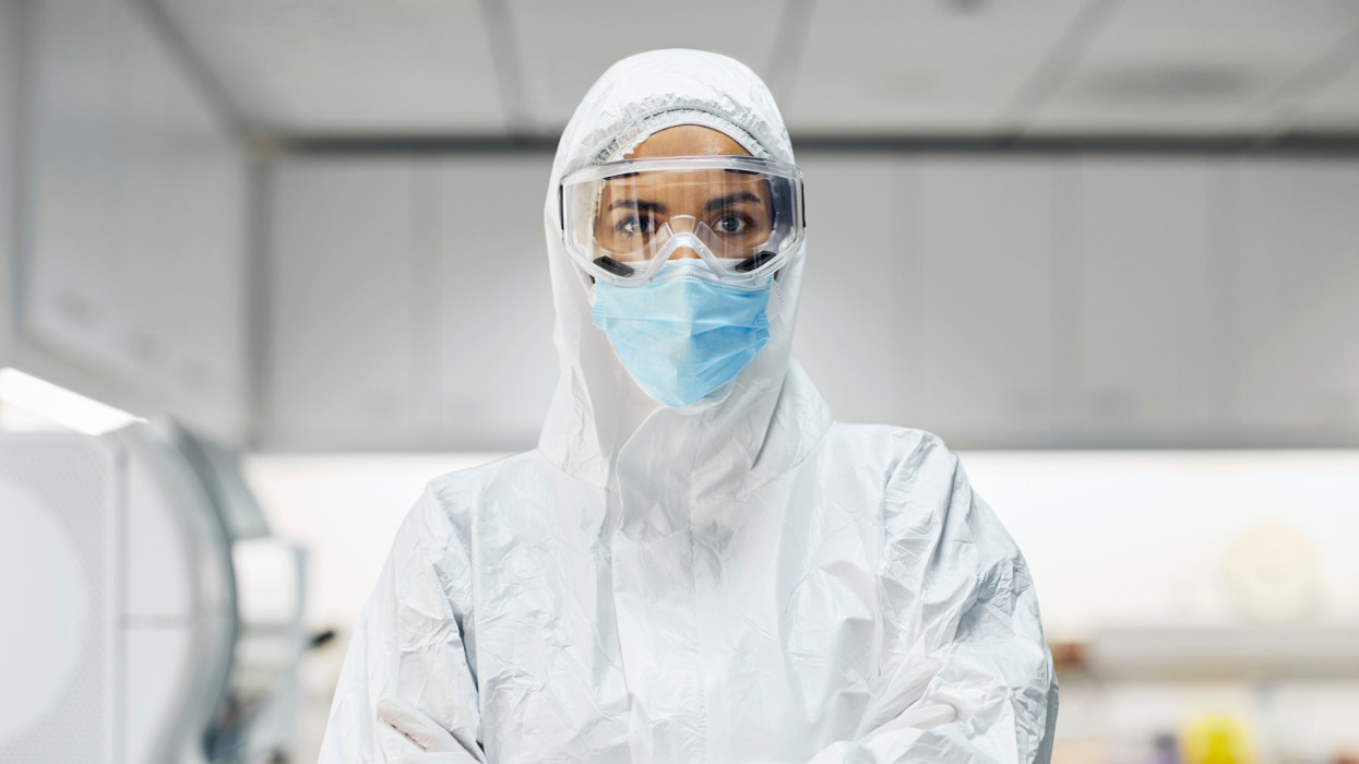 Portrait of female doctor wearing protective suit and face mask. Confident healthcare worker is in laboratory. She is working in hospital during pandemic.