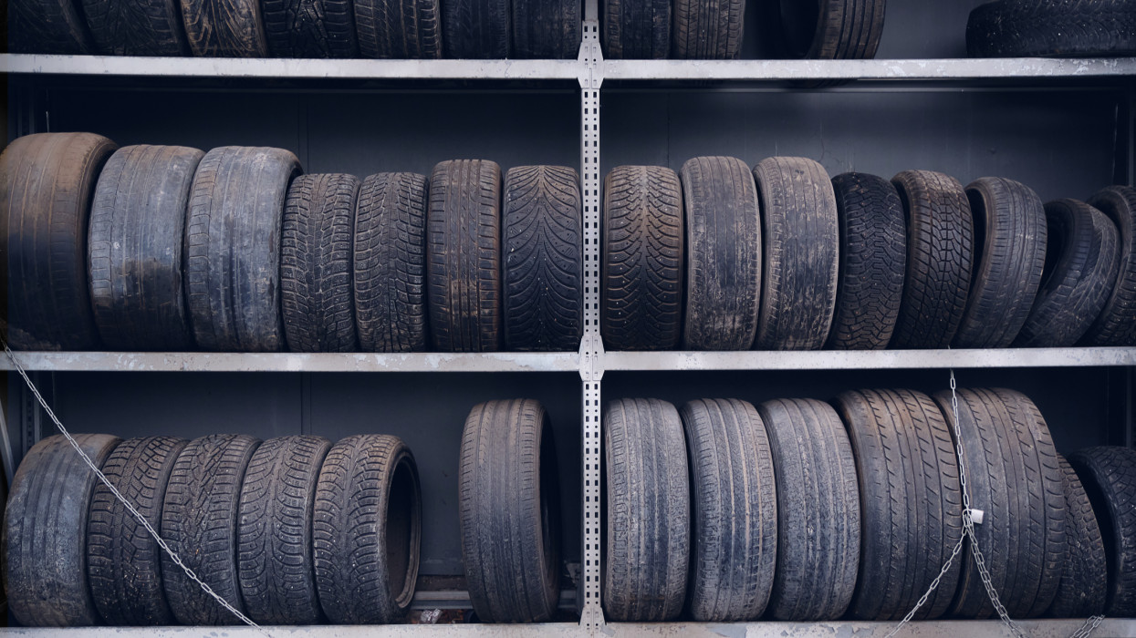 Old worn-out car tires from cars and trucks are stacked in a pile and in a row, stored. Surrender to the secondary use.