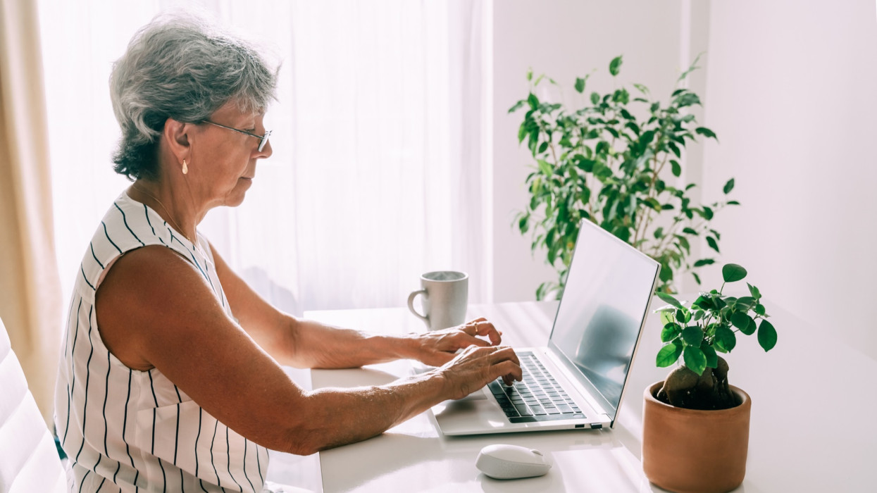 Senior woman sitting with laptop at home. Work and study online for retirees.
