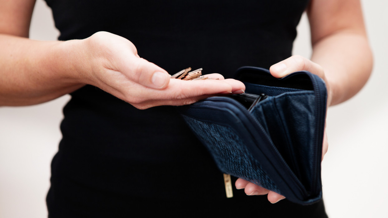 Woman with coins in hand with black leather purse