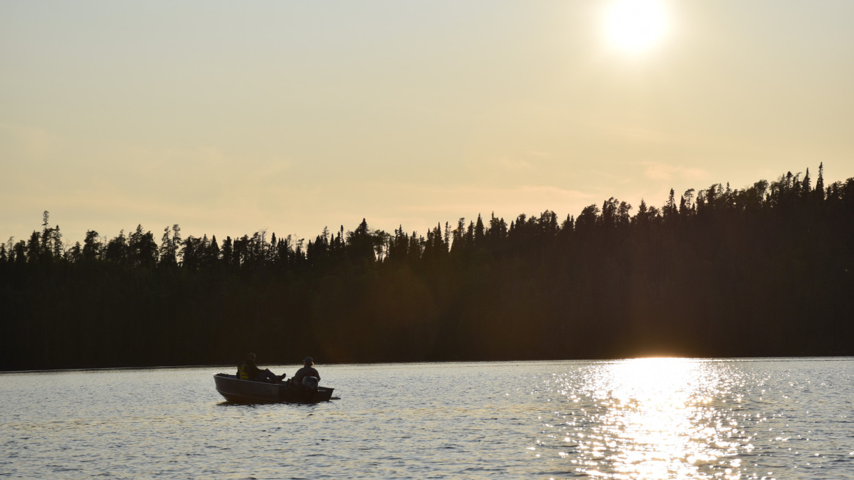 A walleye anger fishing from a boat at sunset
