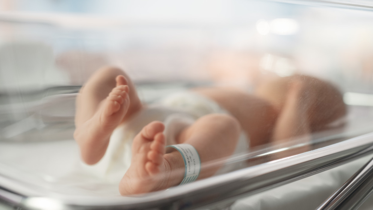 Cute Little Caucasian Newborn Baby Lying in Bassinet in a Maternity Hospital. Portrait of a Tiny Playful and Energetic Child with a Name ID Tag on the Leg. Healthcare, Pregnancy and Motherhood Concept