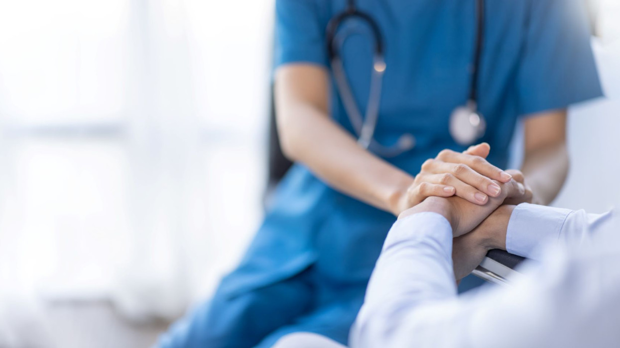 Cropped shot of a female nurse hold her senior patients hand. Giving Support. Doctor helping old patient with Alzheimers disease. Female carer holding hands of senior man