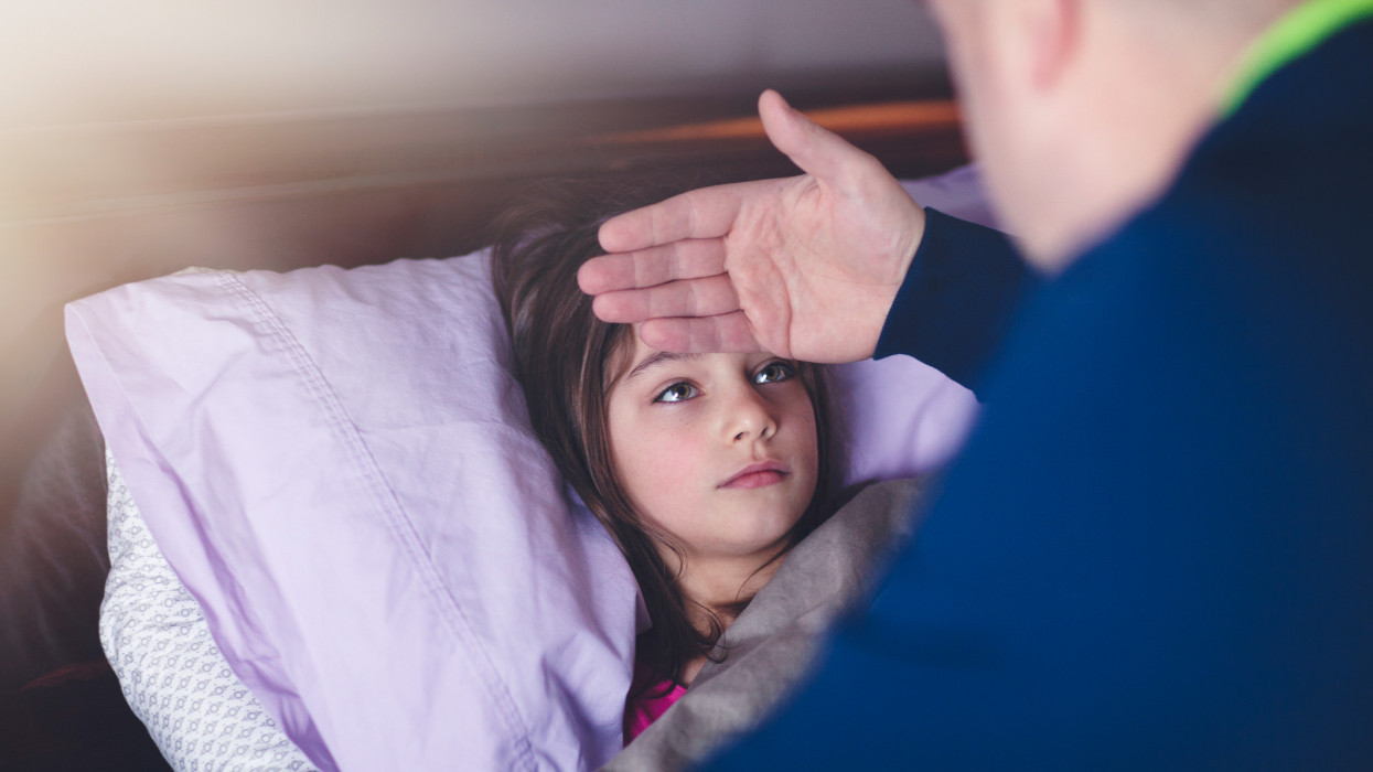 father checking daughters forehead for fever