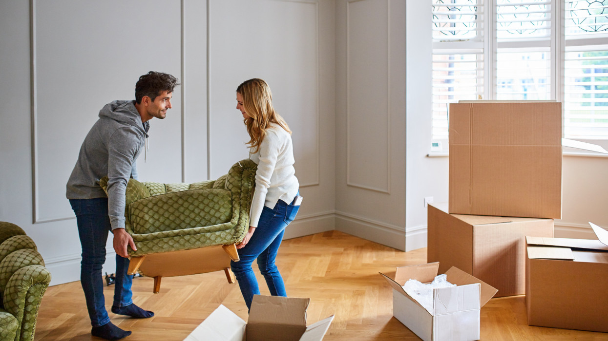 Shot of a happy young couple moving furniture in their new house