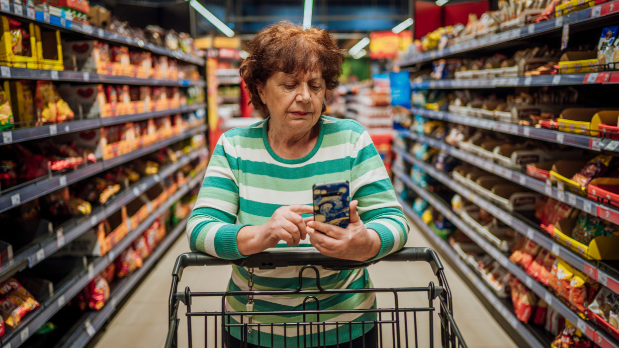 Senior woman checking shopping list on smartphone at the supermarket