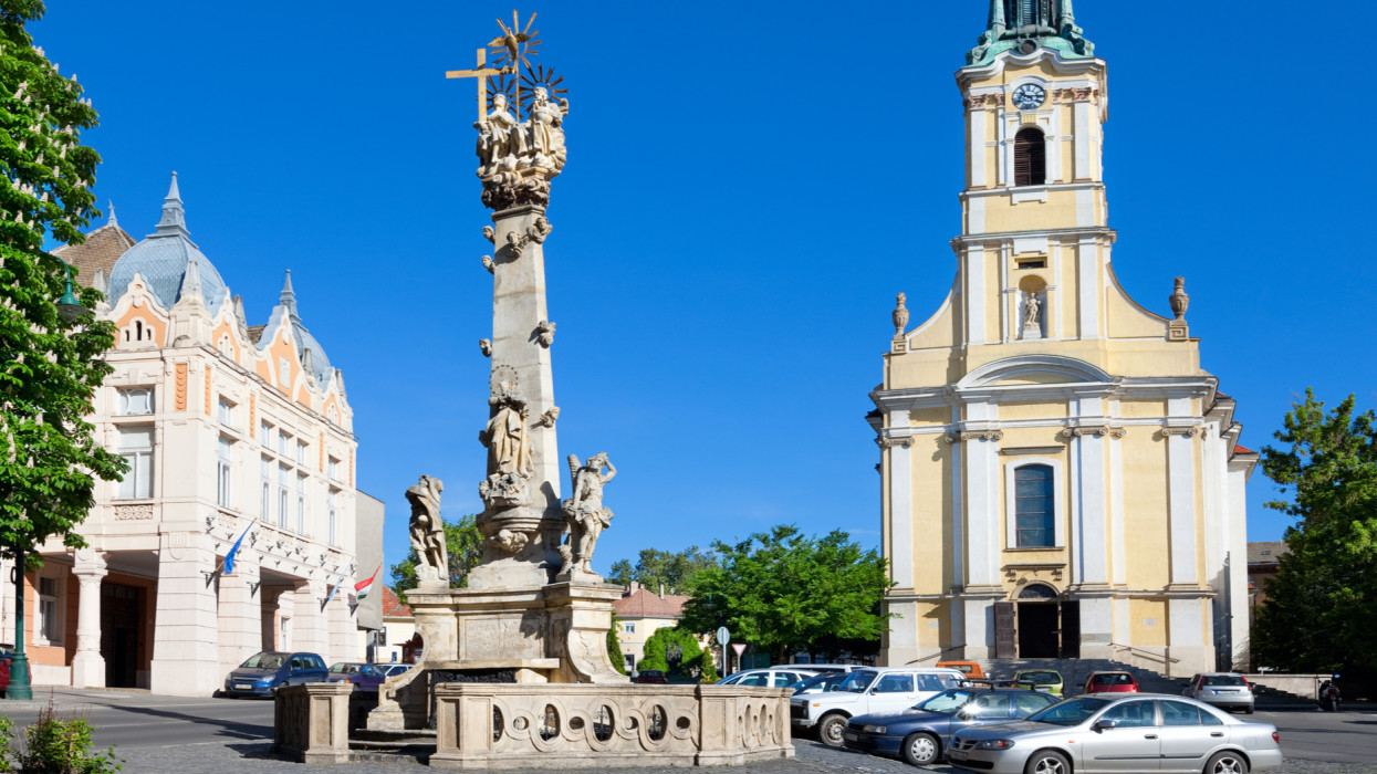 Photo of King Bela Square in downtown Szekszard, Hungary with the Town Hall,  the Holy Trinity Statue (made in 1753) and the Catholic Church.