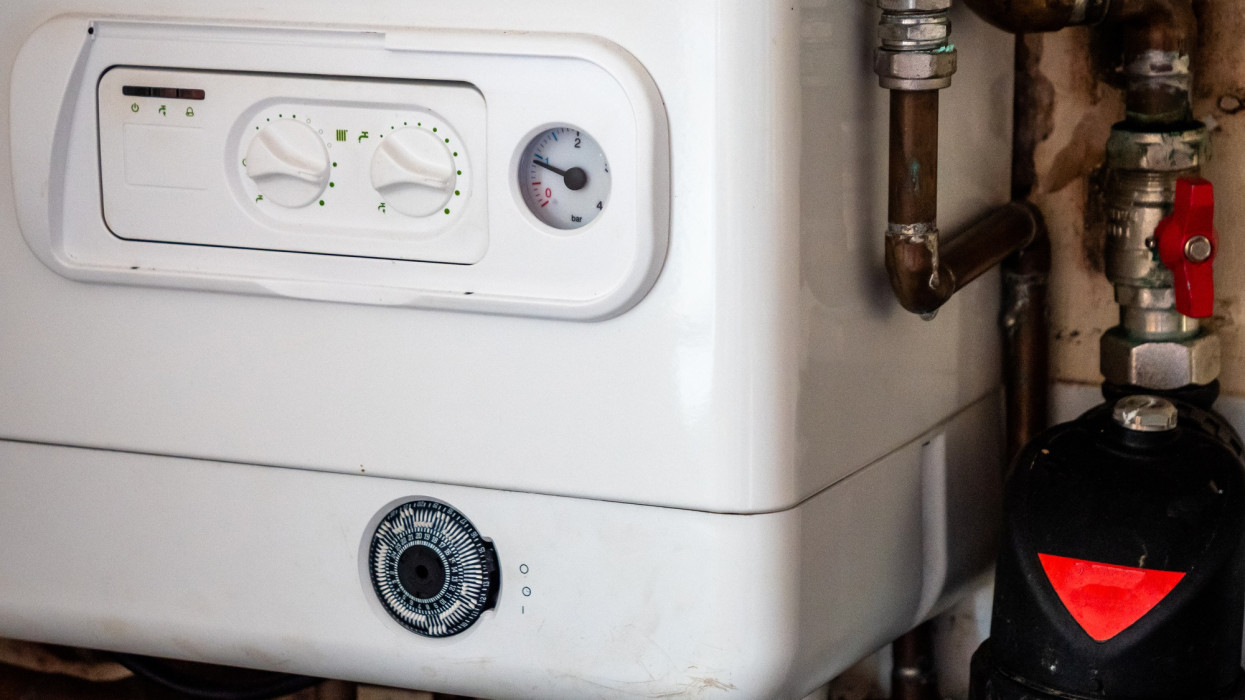 Close up of Gas Small to Medium sized Combi Boiler heating system found in typical family home terrace house in UK. Energy costs are increasing putting financial and budget pressure on families to stay warm. UK government giving support payments to minimise the slip into poverty