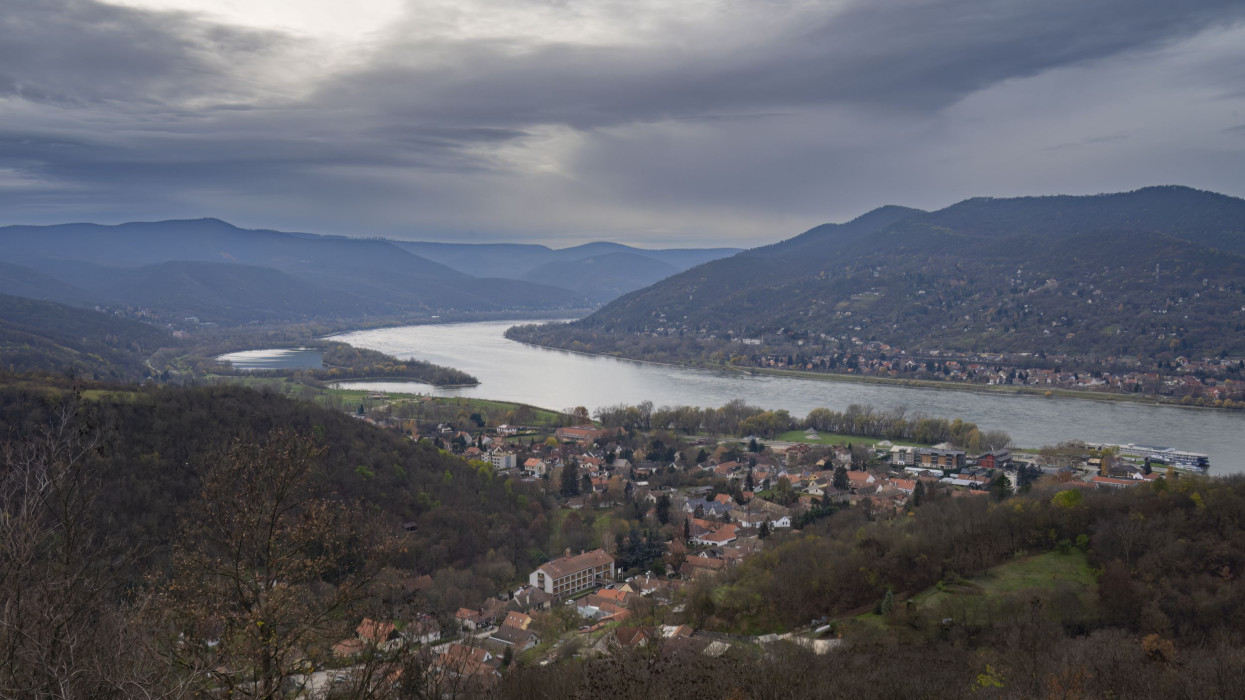 A panoramic landscape of towns on the banks of the Danube river in Hungary, on a hazy, overcast winter day.