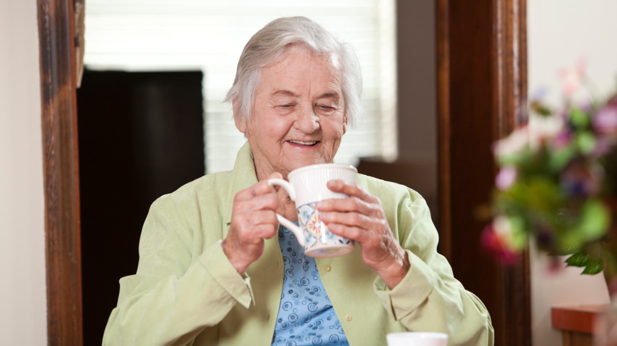 Elderly lady drinking a cup of tea or coffee.