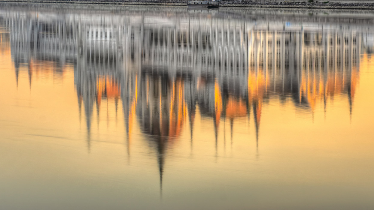 View of Budapest parliament at sunset, reflection on Danube River, Hungary