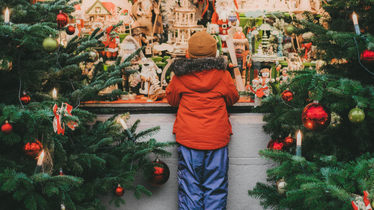 Little  Caucasian boy standing near Christmas tree in Rothenburg in winter
