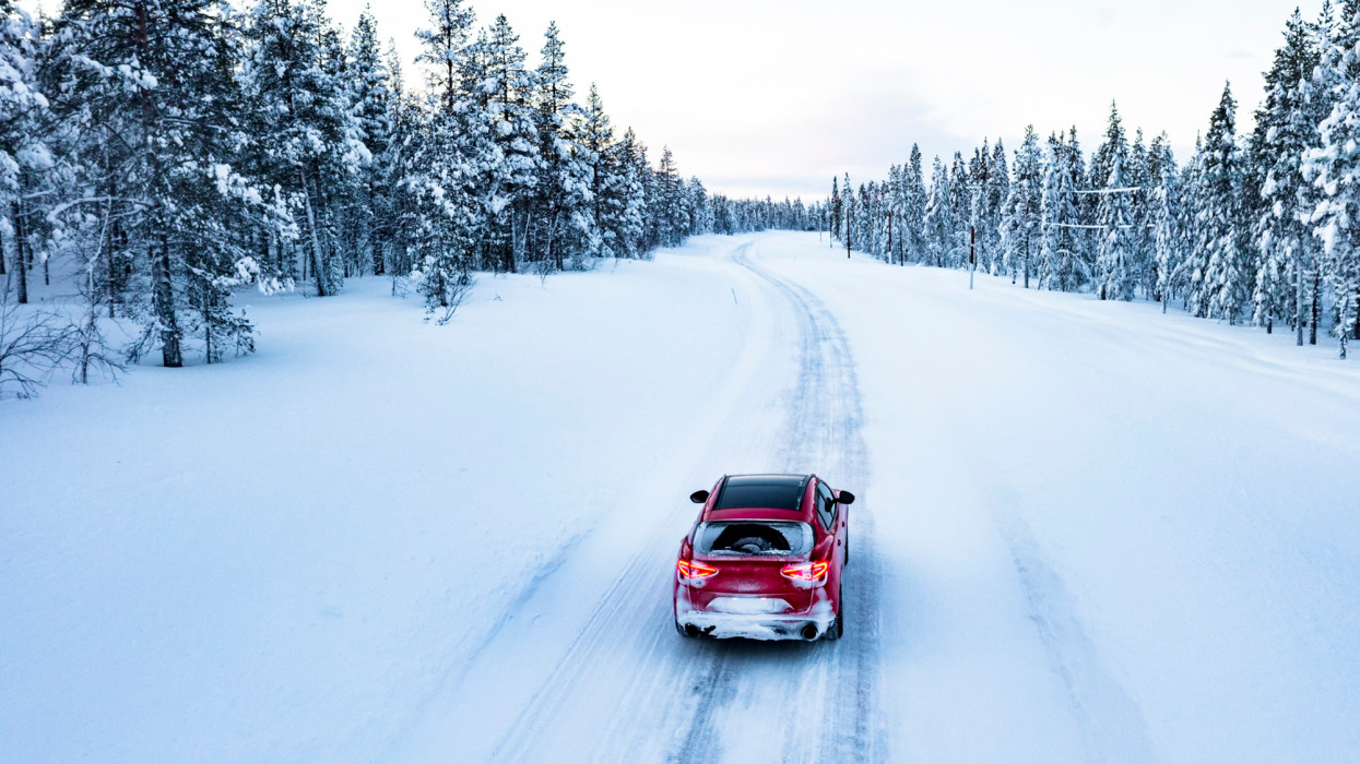High angle view of car traveling on icy slippery mountain road in the winter forest covered with snow, Gallivare, Lapland, Sweden