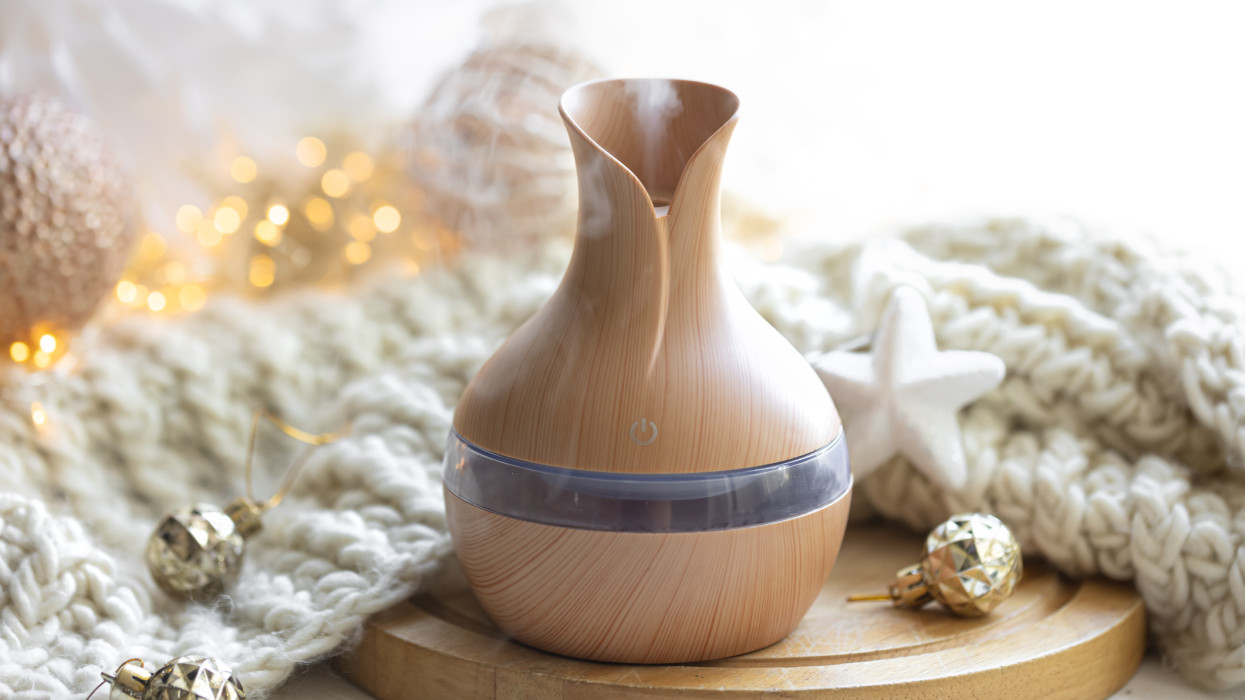 Still life with an aroma diffuser for moisturizing the air, knitted element and Christmas decor details.