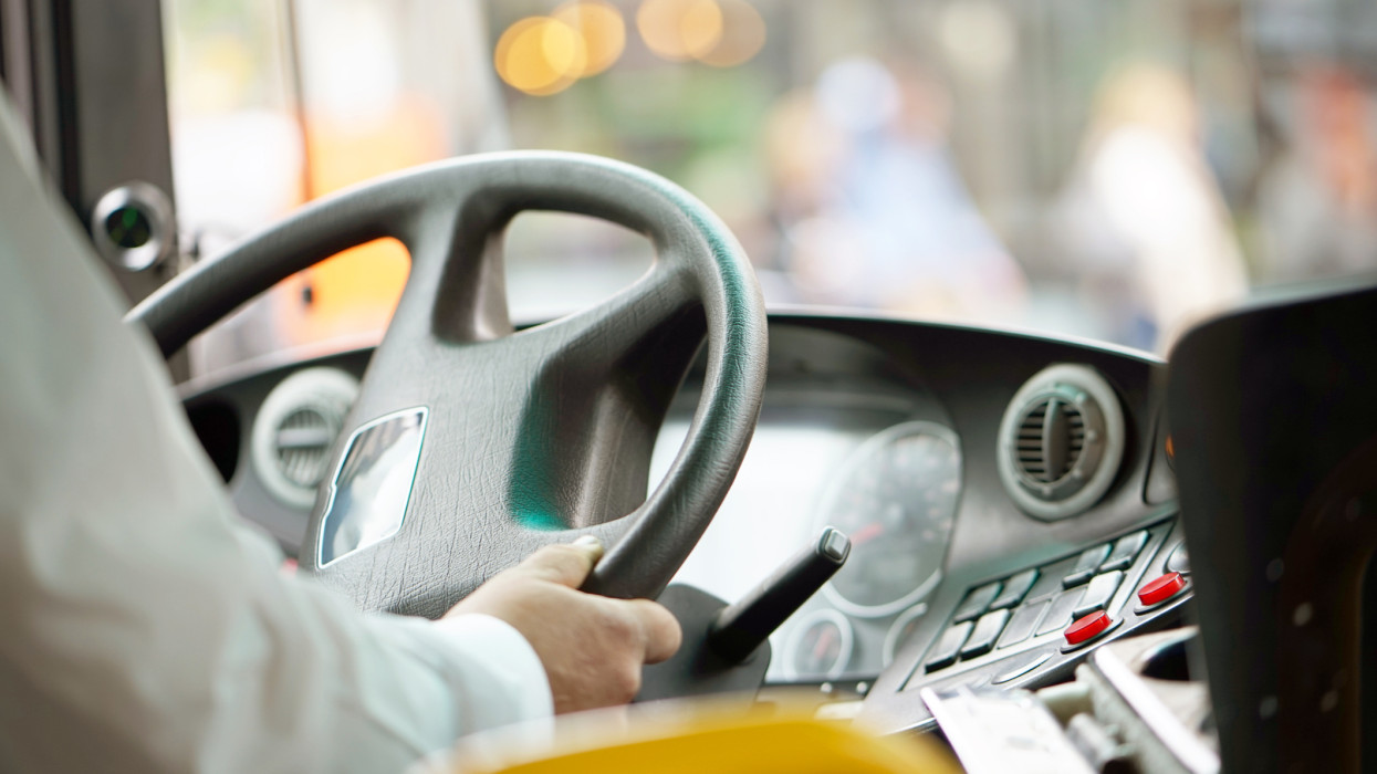 Hands of driver in a modern bus by driving.Concept - close-up of bus driver steering wheel and driving passenger bus