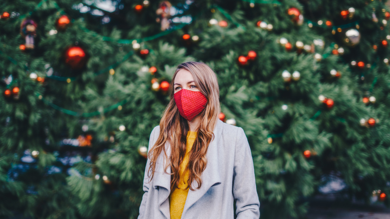 Woman wearing a fabric face mask outdoors in front of the Christmas tree