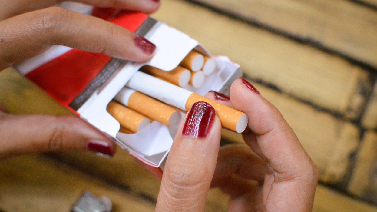 Close up of a womans hands picking up cigarette from a box of cigarettes