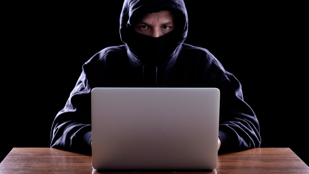 Computer hacker stealing data from laptop. Concept for network security, identity theft and computer crime. Dark background