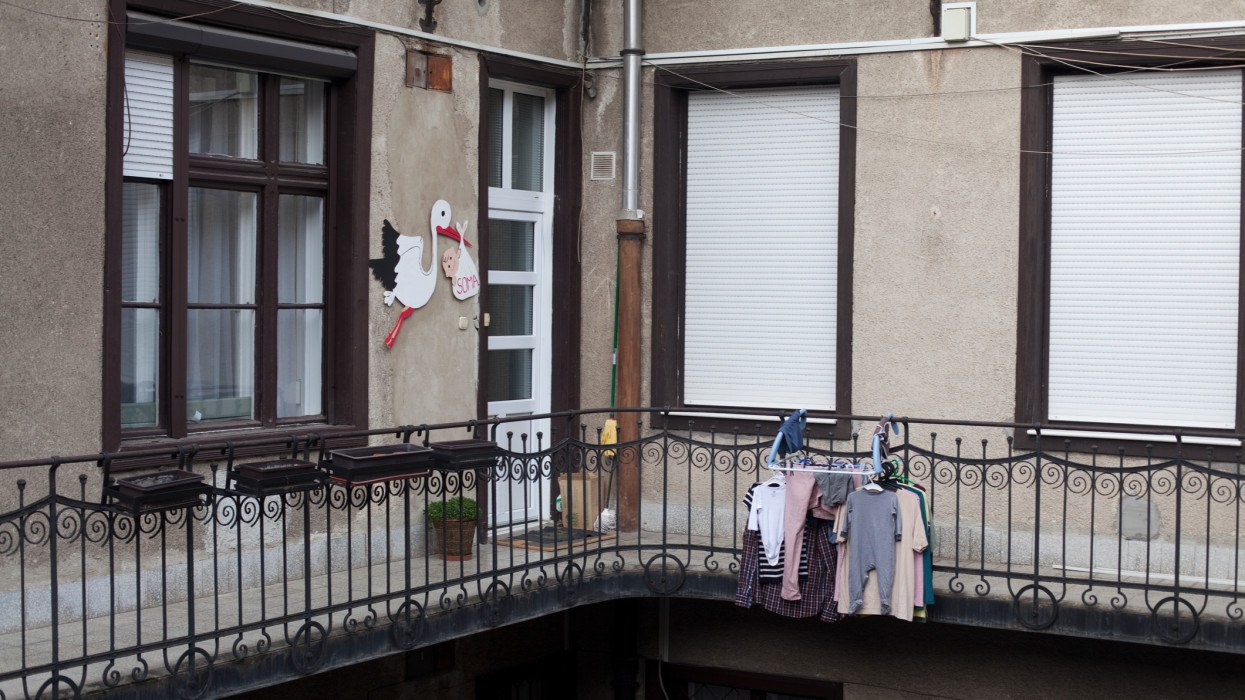 stork brings a baby to the house, where already baby clothes are drying outside the balcony