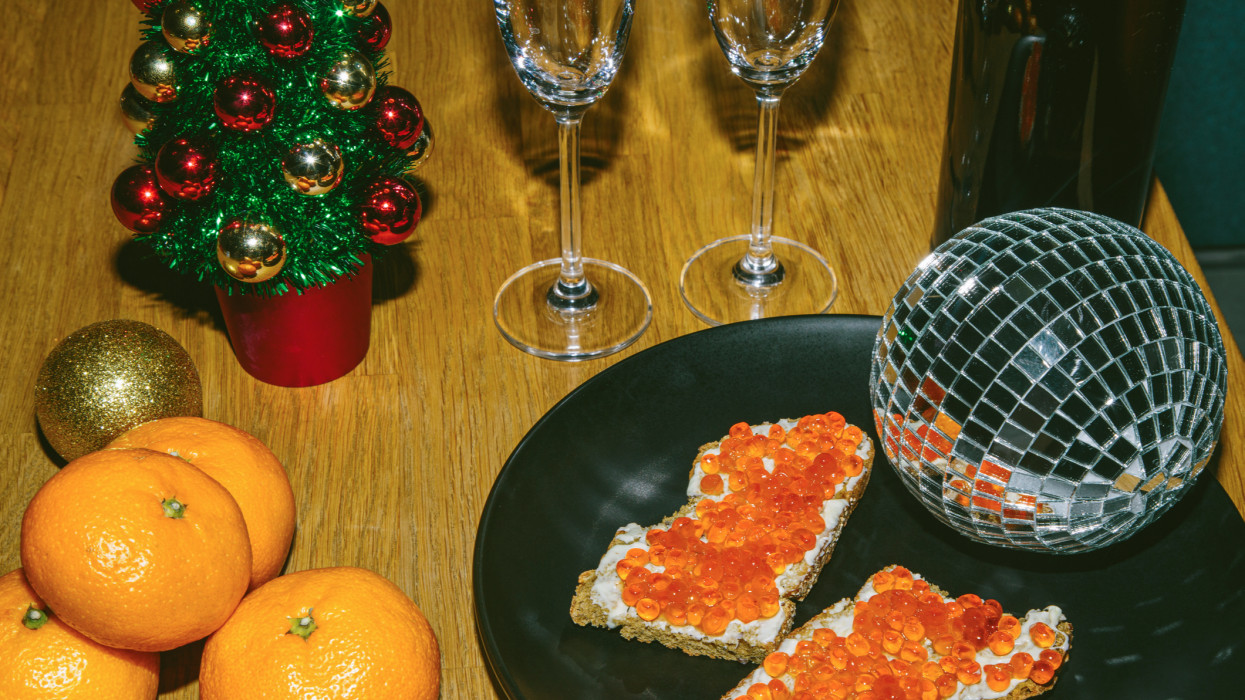 New years table with mandarins, salmon caviar, champagne and Christmas decorations