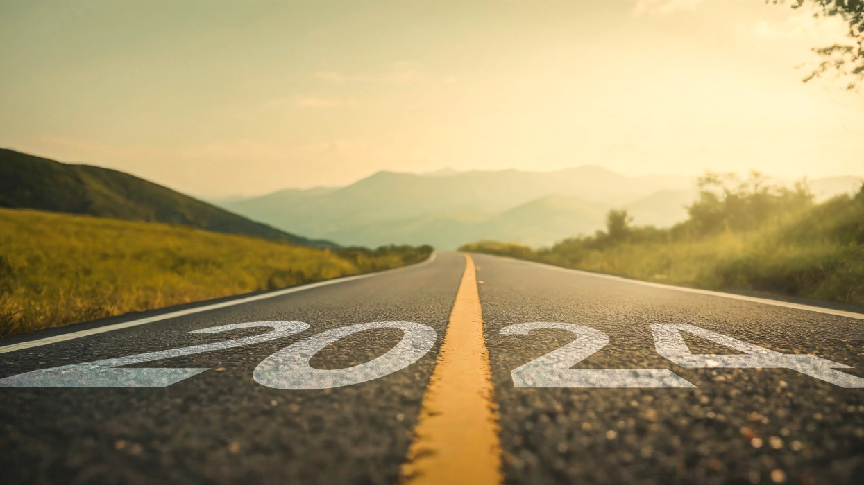 A picturesque road with â2024â prominently displayed, set against a backdrop of majestic mountains and a breathtaking sunrise. This image encapsulates the spirit of the New Year 2024, symbolizing change, fresh starts, and the excitement of embarking on a new journey.