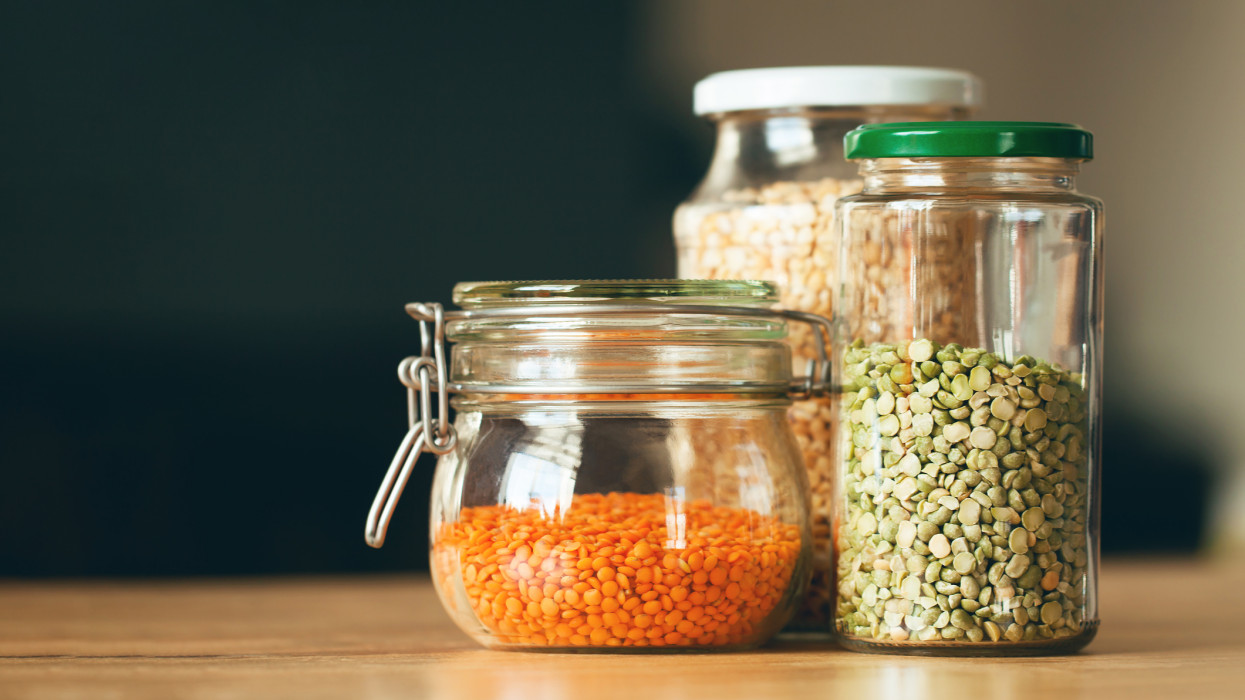 Glass jars with beans in the minimalistic interior. Peas and lentils as sources of vegetable protein. Zero waste concept, plastic-free, eco-friendly shopping, vegan