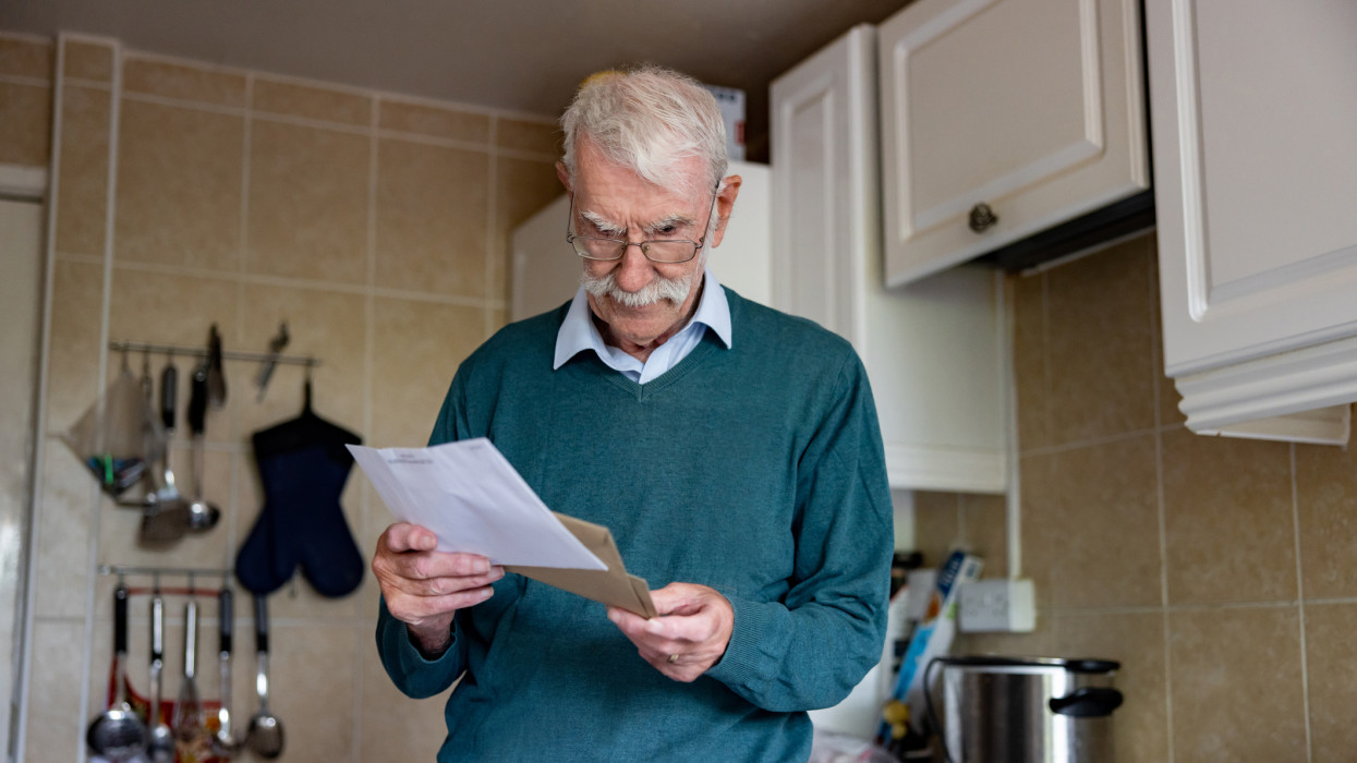 Portrait of a senior man at home reading a letter he got in his mail - domestic life concepts