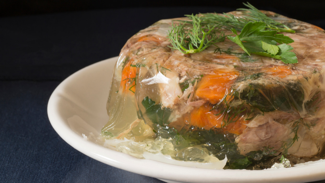 Aspic meat in a white plate on the table. Food on a black background