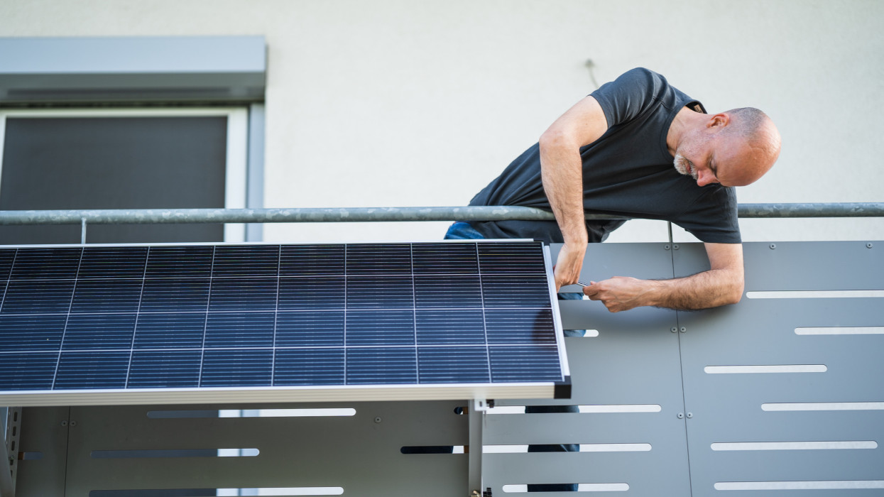 man installing adjustable solar panel on balcony of his house