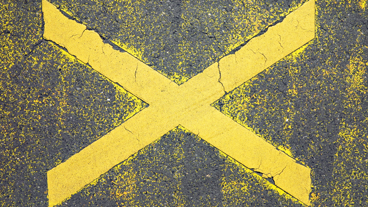 Close-up of a road marking in Paris, France. Weathered and scratched yellow paint on street. Rough-textured. Natural light and colors.