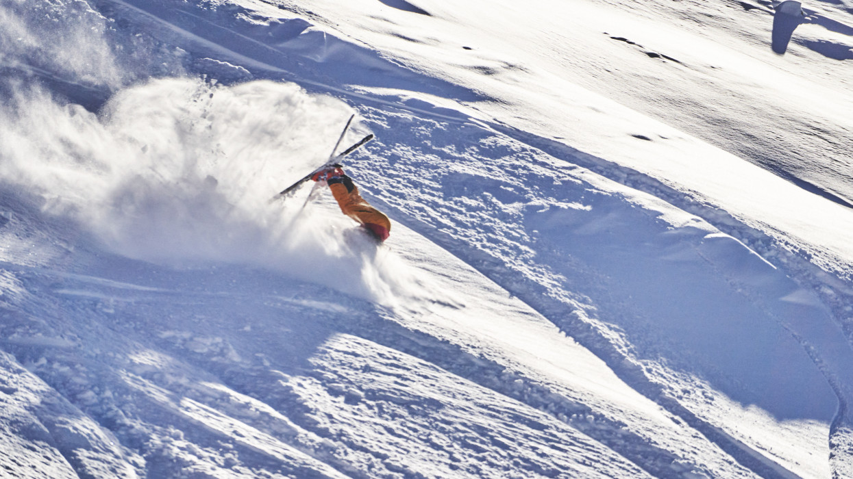 He creates a cloud of snow as he tomahawks down the slope at speed, in the snowy Swiss Alps