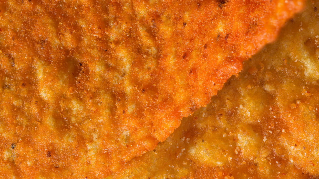 Macro shot detail of textured, cheese flavored orange corn chip