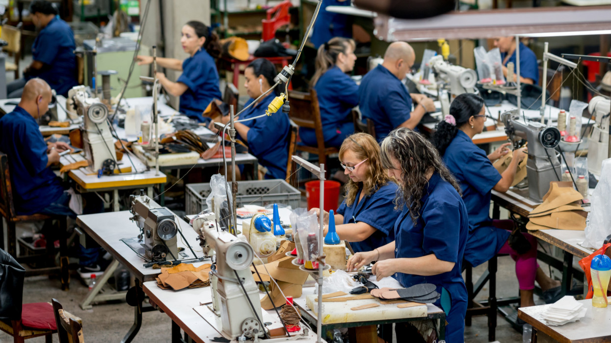 Group of Latin American manual workers working at a shoe-making factory