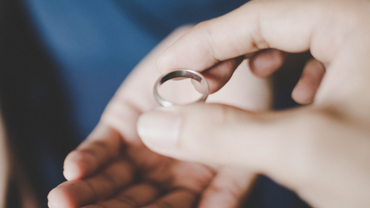 A close-up view of a young couples hands holding a wedding ring, a concept of divorce