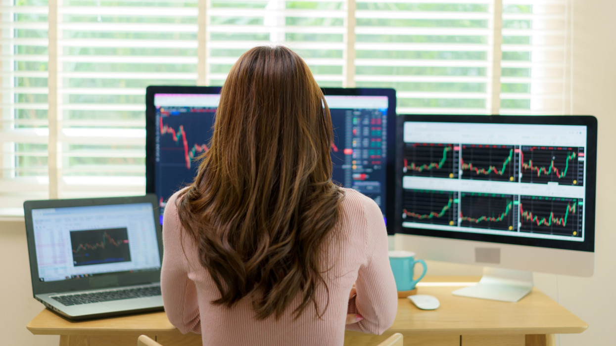Happy Asian woman gleefully examines a promising stock graph. Her confident gaze reflects the satisfaction of making informed financial decisions, embodying the spirit of astute investment and financial empowerment