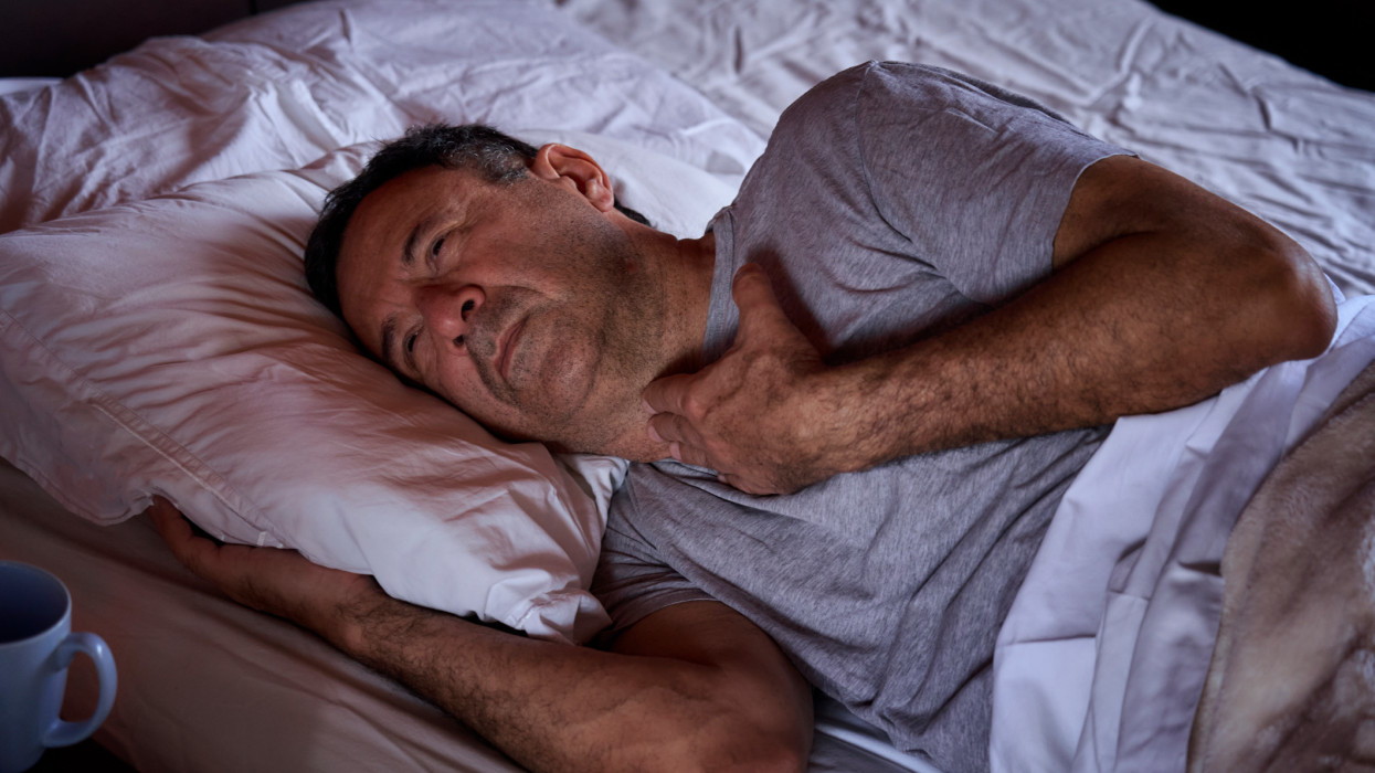 Despair Hispanic senior man  laying on bed with sore throat